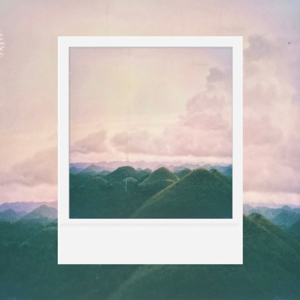 The distant breath of land layered within an analog film frame featuring the flow of green mountain ridges undulating like waves