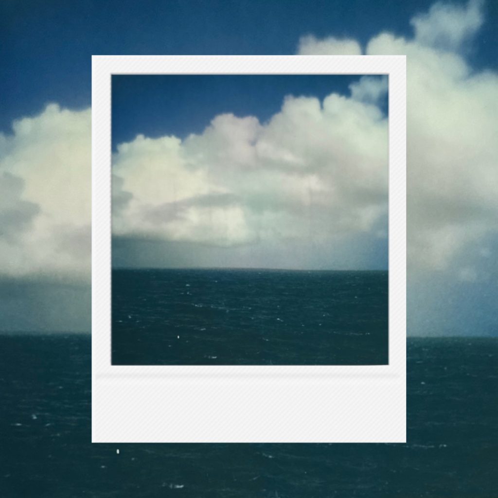 A quiet shimmer crafted by cumulonimbus clouds and blue waves hanging at the end of the horizon.