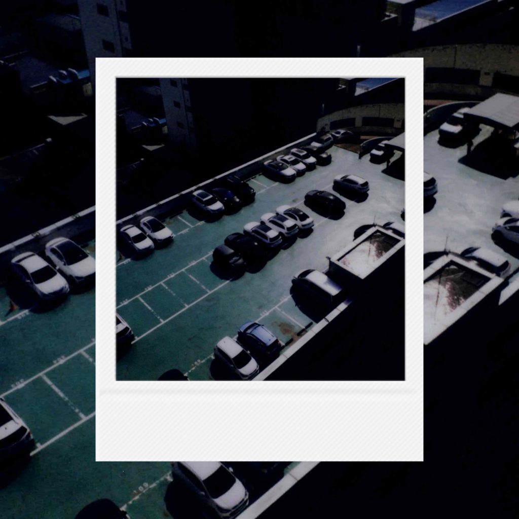 A cross-section of daily life frozen in cold analog film textures featuring the silence of cars parked along teal-shaded rows