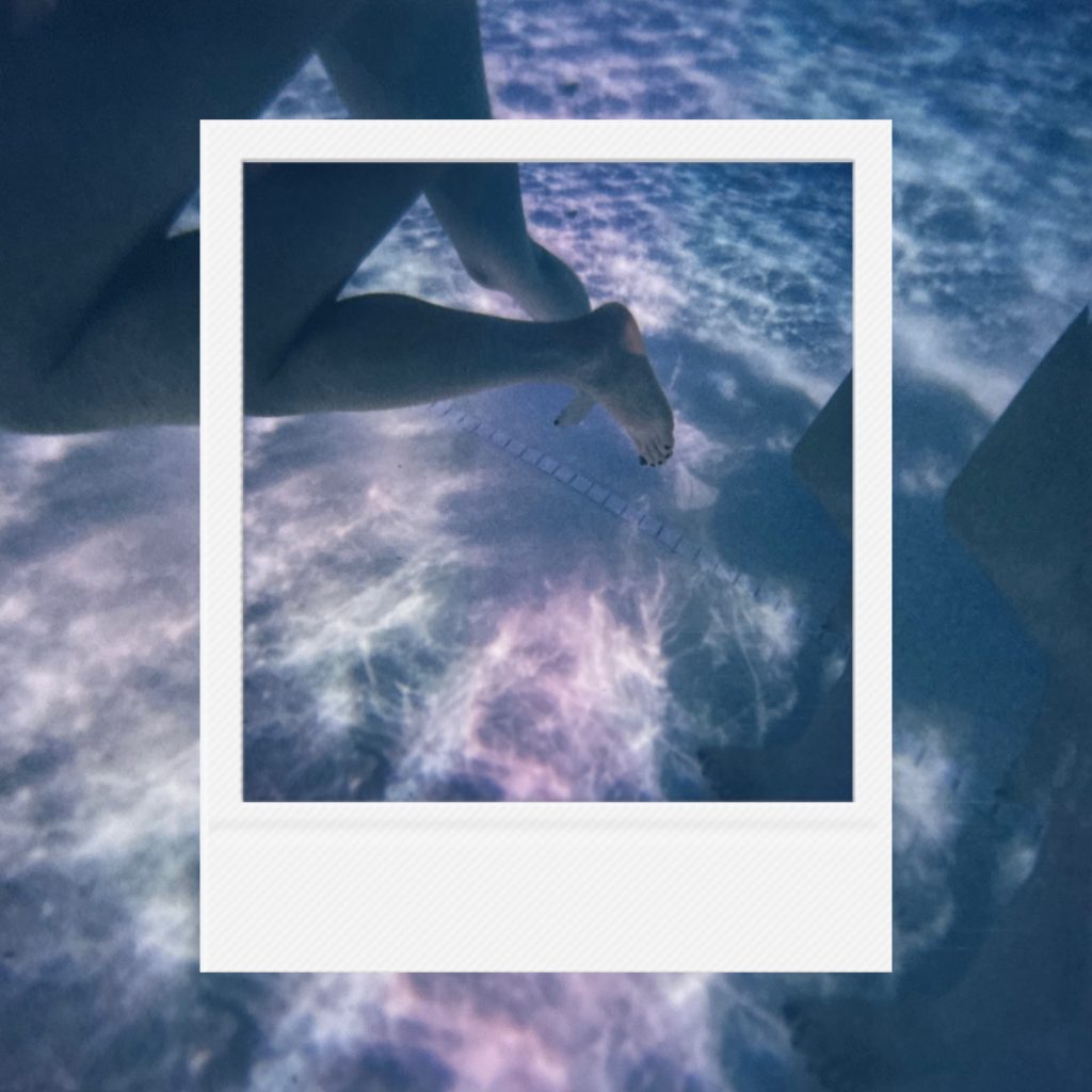 A moment of free youthful immersion within an analog film frame featuring blue silence beneath swaying waves where all noise is muffled