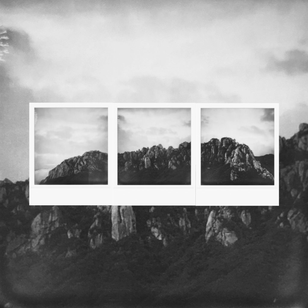 The majesty of rocky mountain ridges rising above clouds capturing eternal stillness layered within analog monochrome film frames
