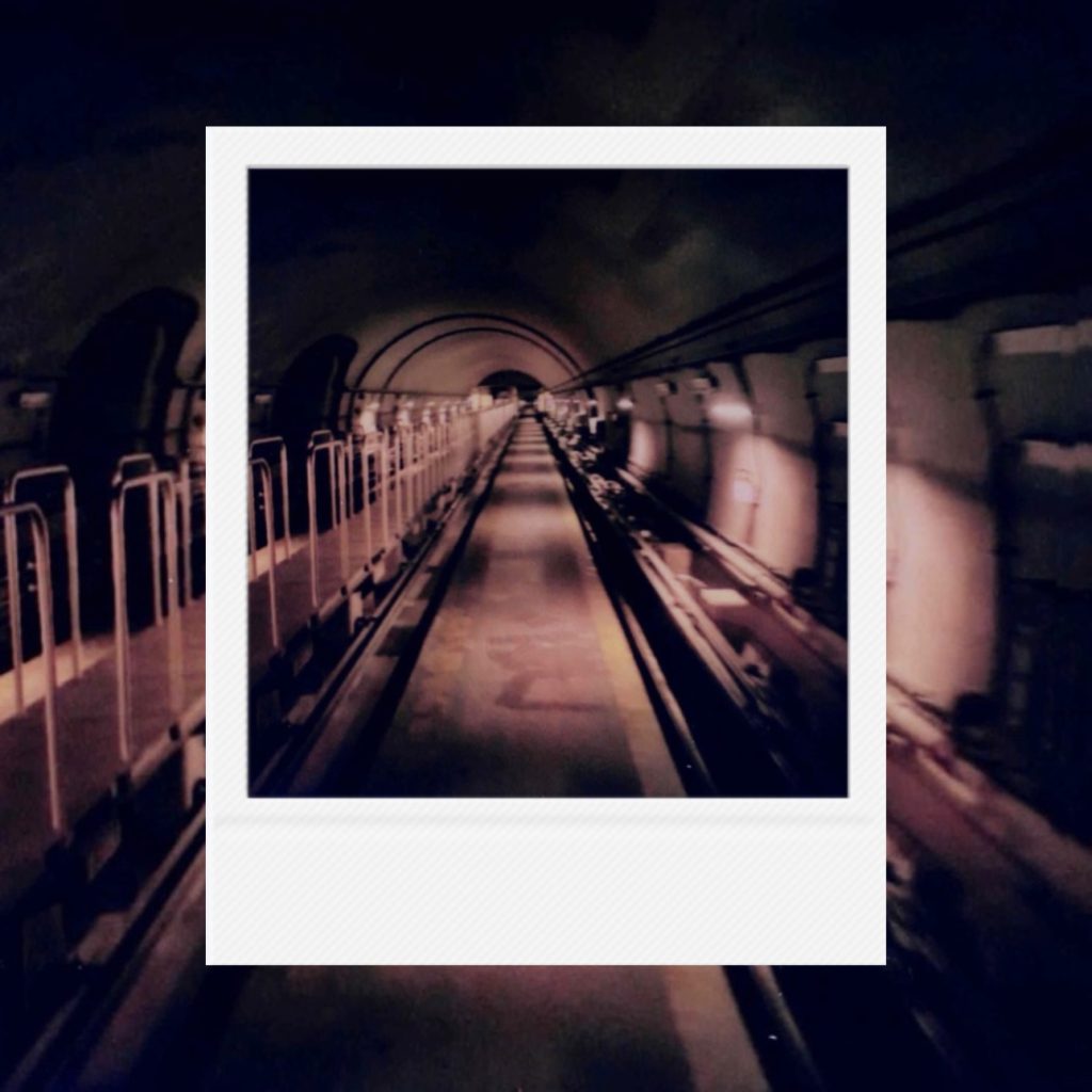 The distant trajectory of light pouring toward the vanishing point of an endless underground tunnel capturing a static record of time within an analog film frame