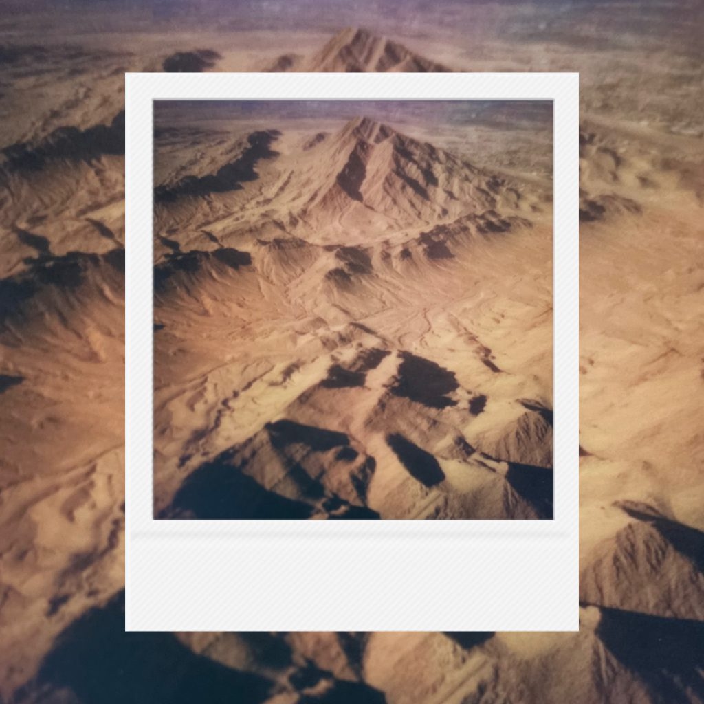 The ancient quiet breath sleeping beneath the red dust capturing the stillness of layered mountain ridges within an analog film frame