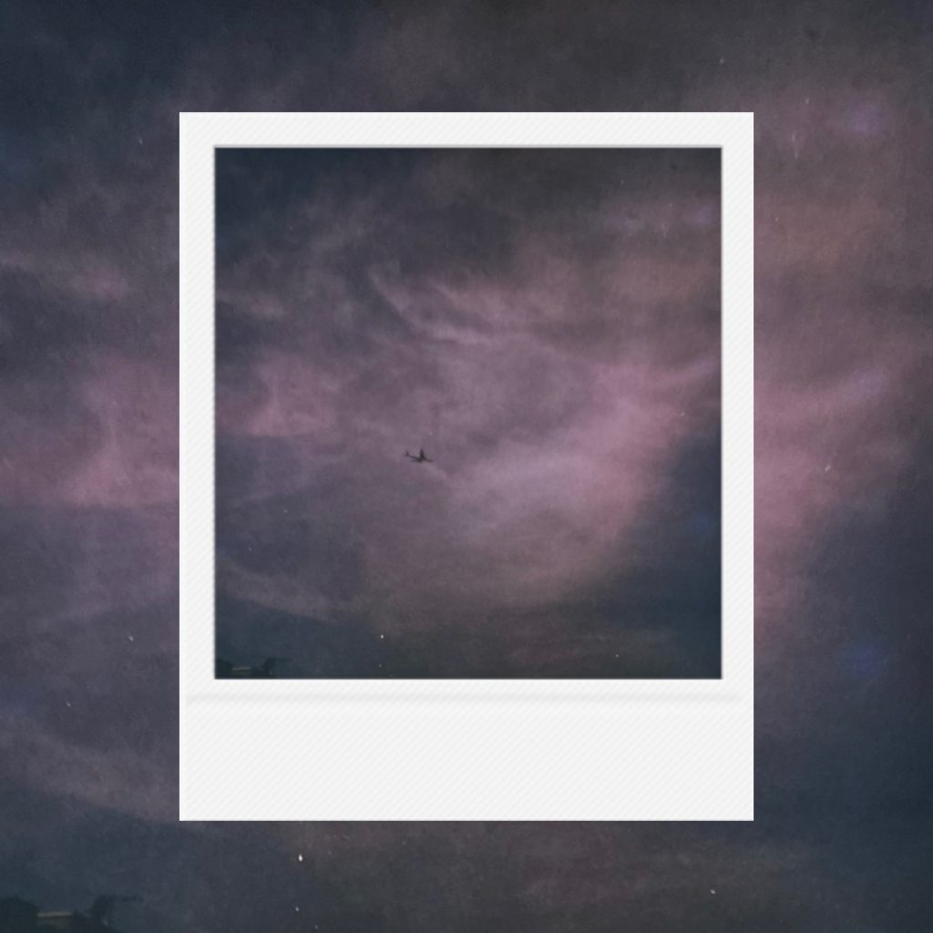 A distant silhouette crossing a dreamlike sky with fading shades of violet and blue, carrying a quiet sense of movement, solitude, and endless horizon presence